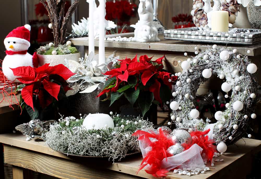 Elige una mesa para hacer un bello arreglo con adornos en tonos blanco y plata mezclados con las flores de navidad.